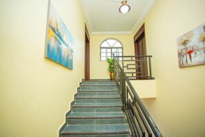 A staircase with a handrail, a potted plant, and two paintings on the walls.