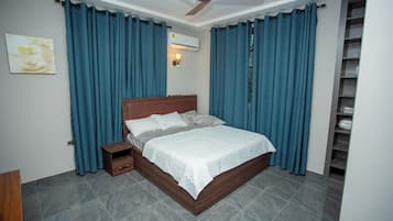 Een slaapkamer met een bed, nachtkastje en een plafondventilator.