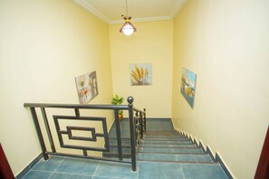 A staircase with a metal railing, blue tiles, and artwork on the walls.