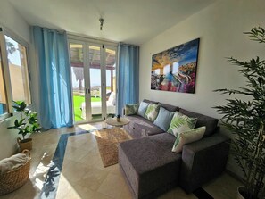 A living room with a sofa, a coffee table, and a view through a glass door to an outdoor area. - Beautiful Sea Views House in La Caleta (CN)