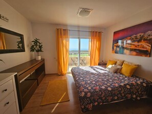 A bedroom with a bed, a desk, a chair, a plant, and a view of the outdoors. - Beautiful Sea Views House in La Caleta (CN)