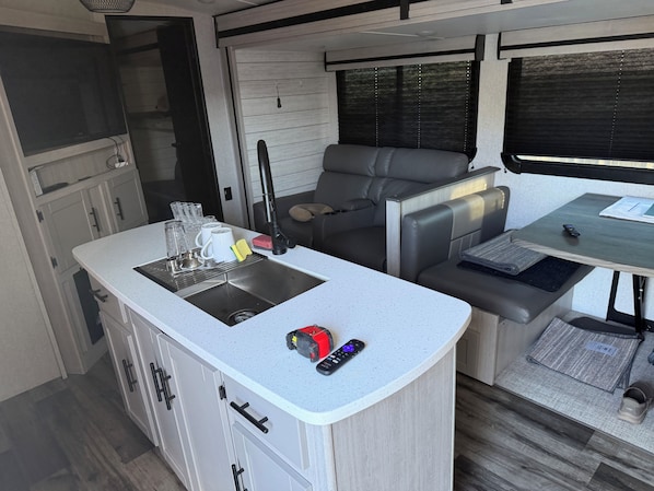 A compact kitchenette with a sink, a small dining area with a table and chairs, and a seating area with a sofa. - Perfect campground for a relaxing outdoor escape in Huntingdon. (Huntingdon)