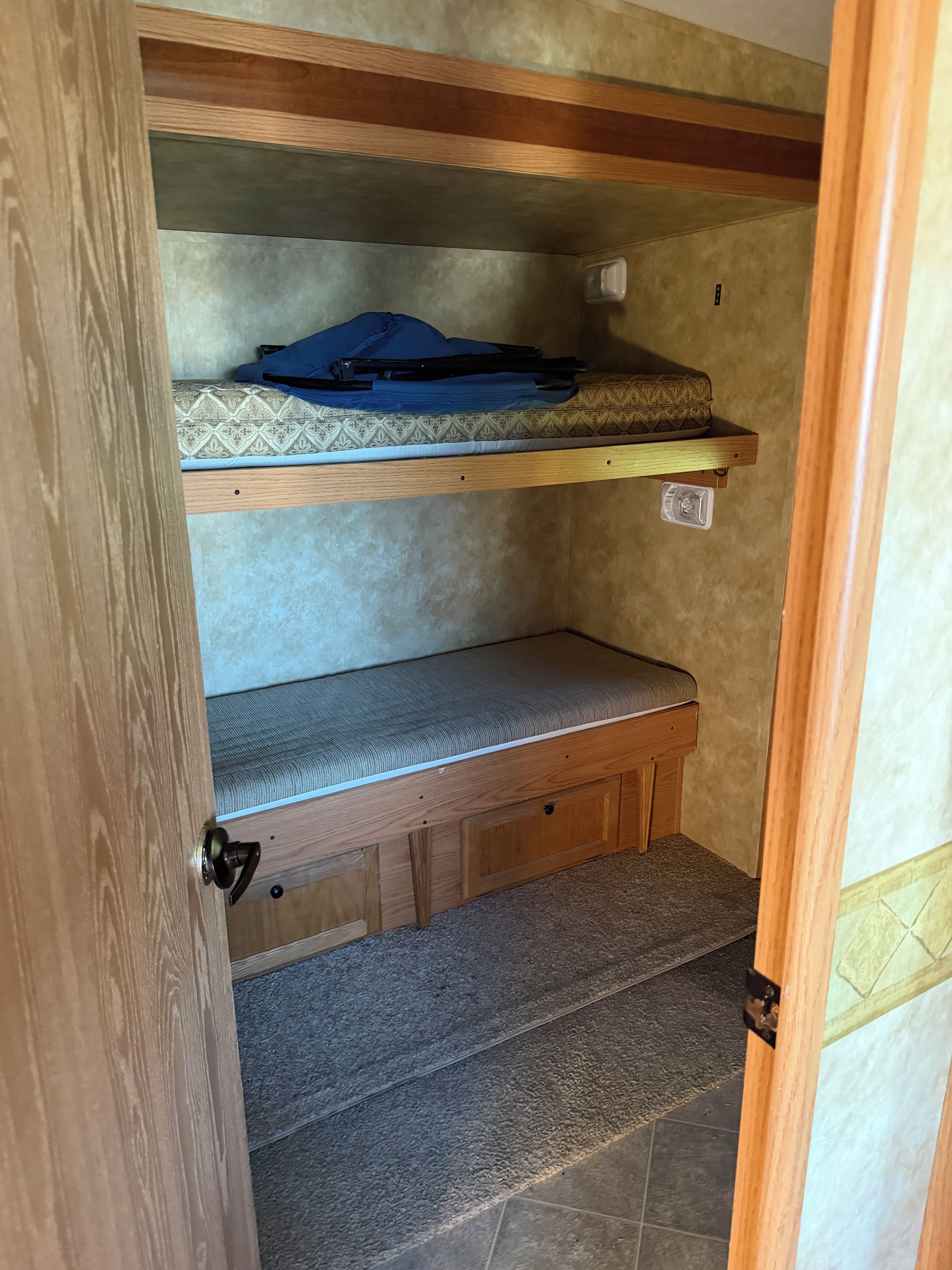 A compact, multi-level sleeping area with a bench and a shelf, featuring a door with a handle.