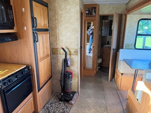 A compact RV kitchen with a stove, microwave, and vacuum cleaner. - Perfect campground for a relaxing outdoor escape in Huntingdon. (Huntingdon)
