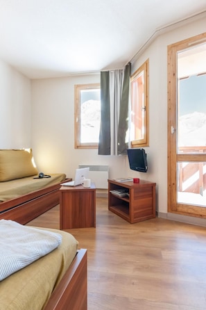 A room with a bed, a desk, a chair, a television, and a window with a view of mountains. - Wifi, 10m from ski slopes, sauna, hammam, ski locker, 35-40m², Val Thorens (Val Thorens)