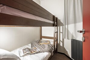 Ein Schlafraum mit Etagenbett, auf der unteren Etage liegen ein Buch und ein Schachbrett.