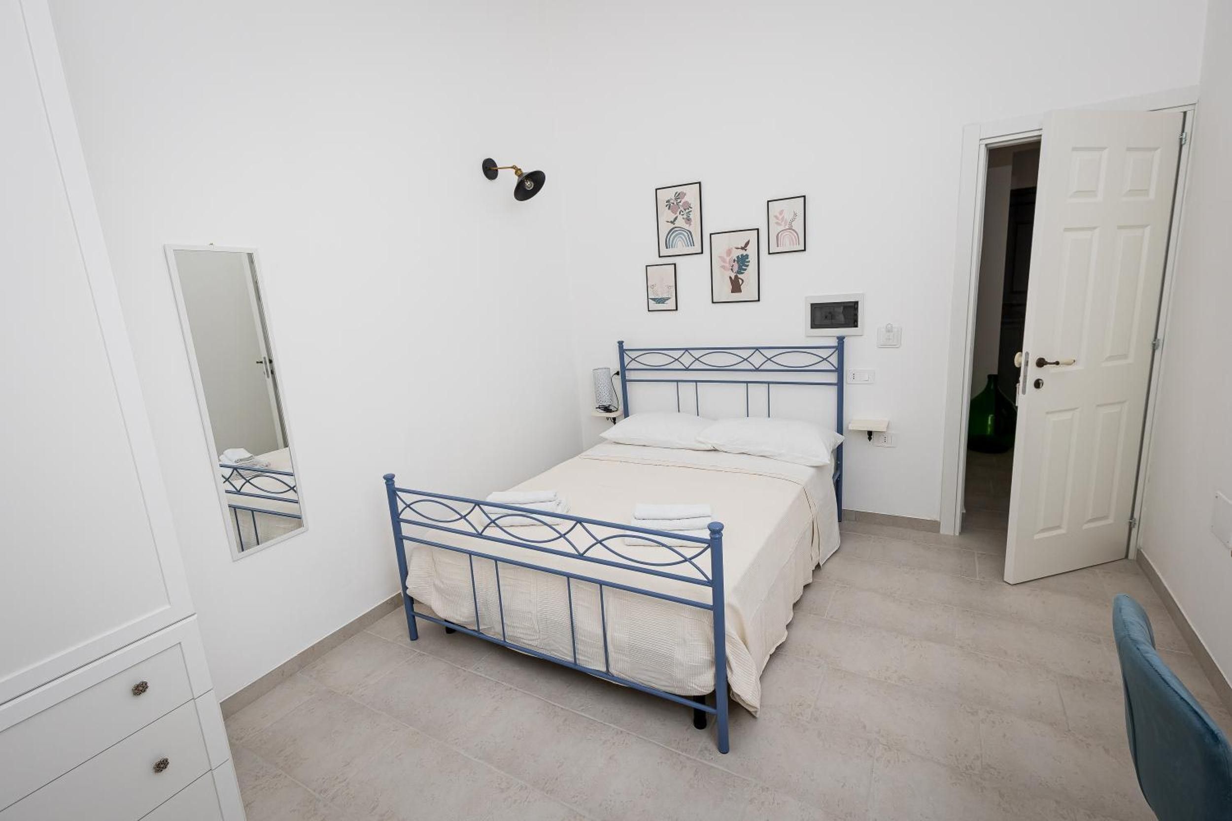 Une chambre à coucher comprenant un lit, une commode, un miroir et une porte donnant sur une autre pièce.