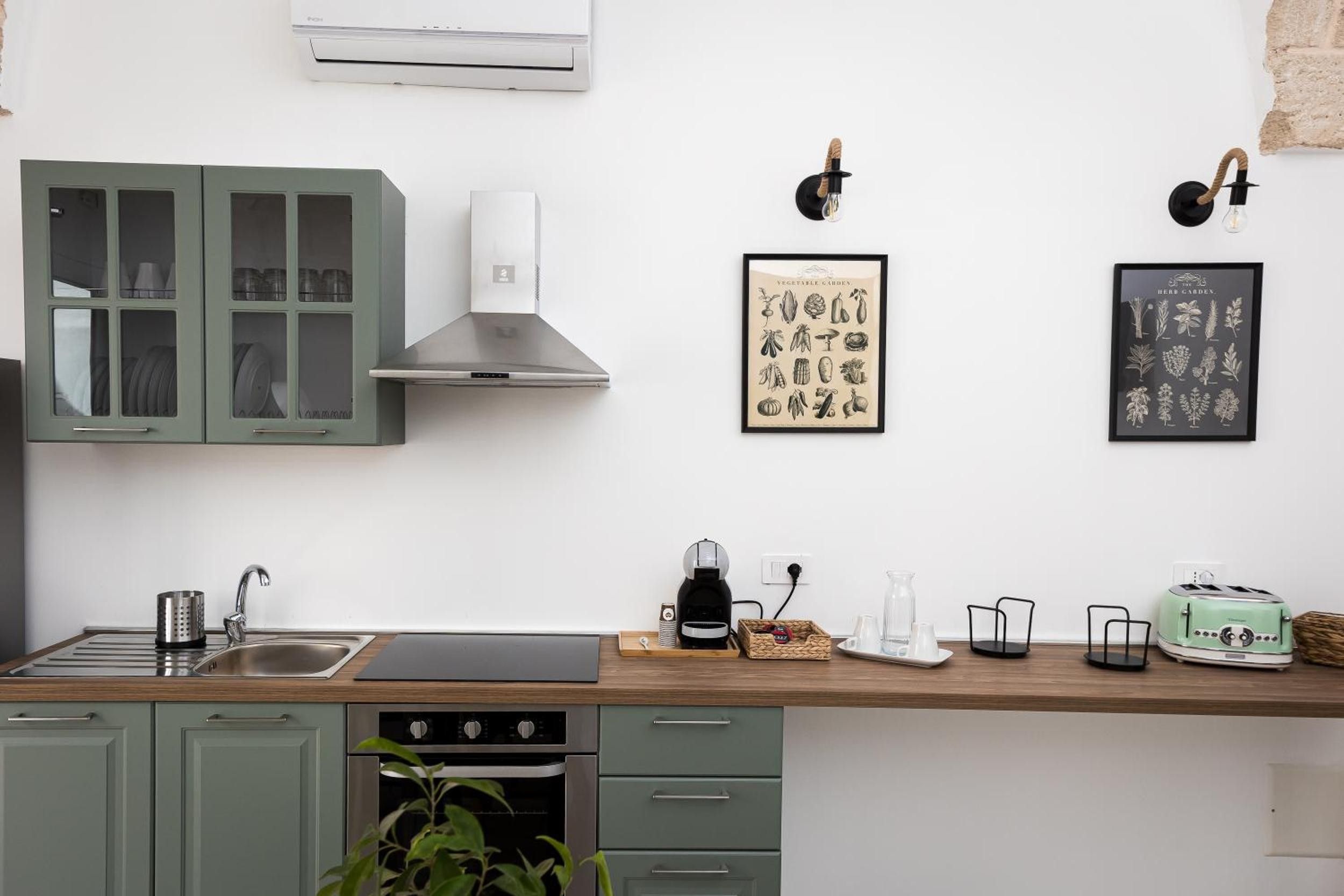 Una cocina equipada con pileta, estufa, alacenas y cafetera.