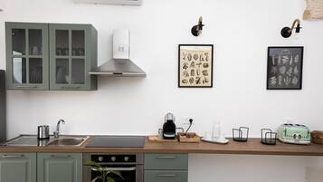 Una cocina equipada con pileta, estufa, alacenas y cafetera.