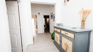 Passadís amb una porta blanca, un armari blau amb motius florals i un vas amb rosegons secs.