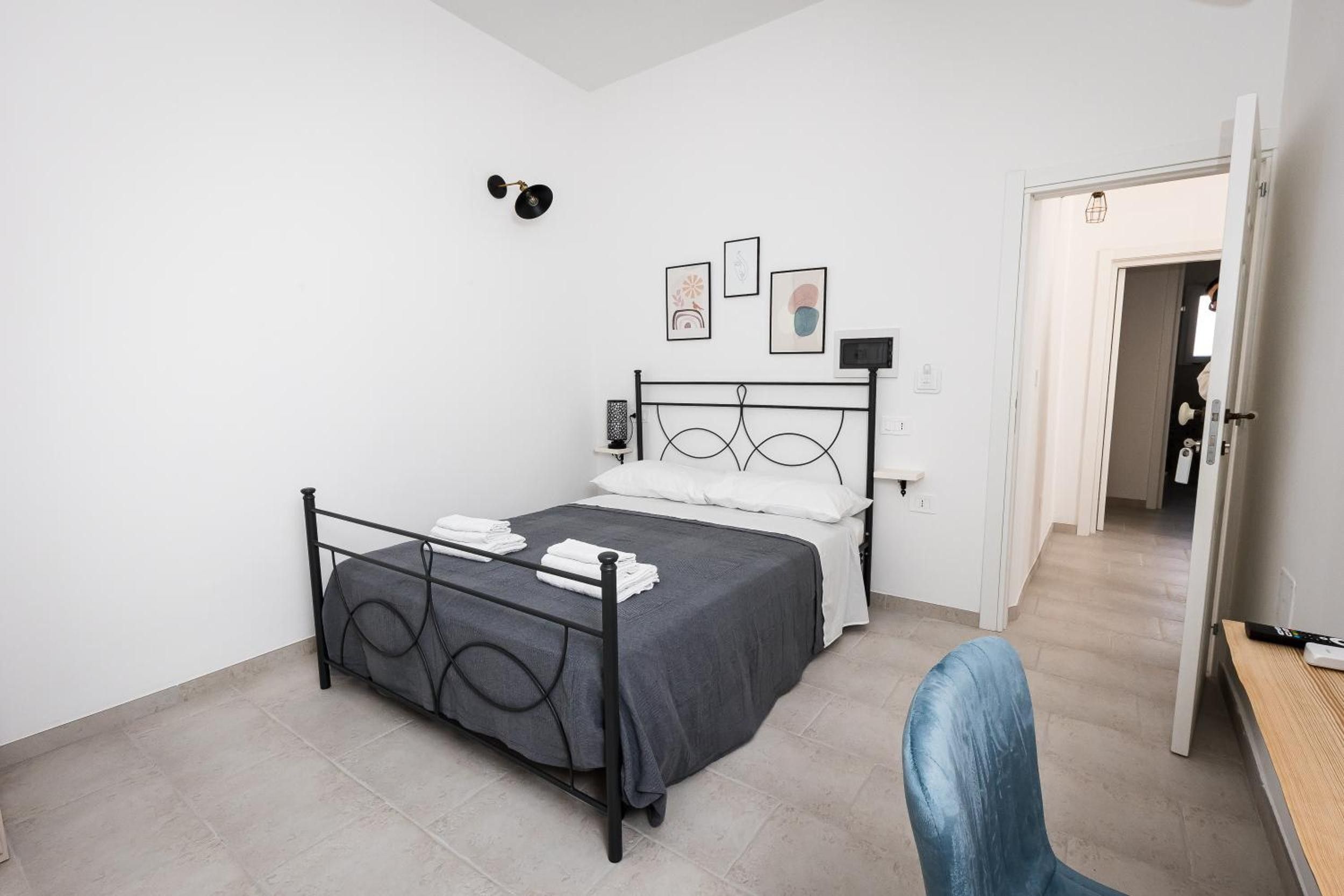 Et soveværelse med seng, stol, dør og gang.