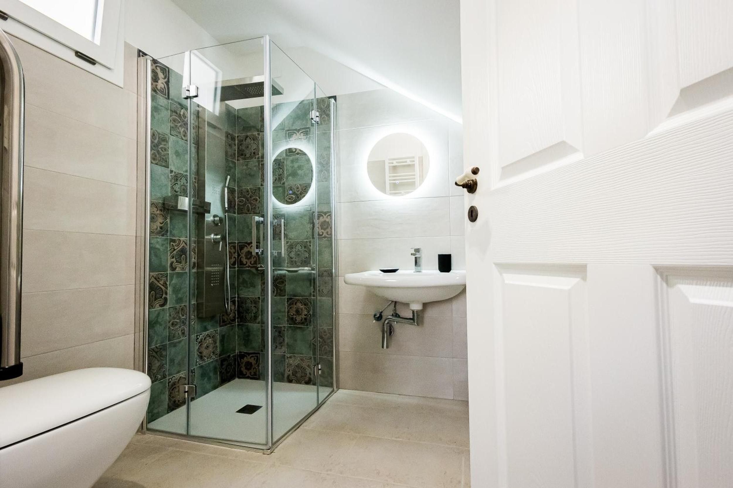 Ein Badezimmer mit einer Duschkabine, einem weißen Waschbecken und einer Toilette.