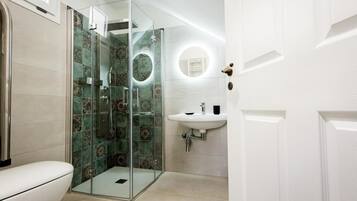 Ein Badezimmer mit einer Duschkabine, einem weißen Waschbecken und einer Toilette.