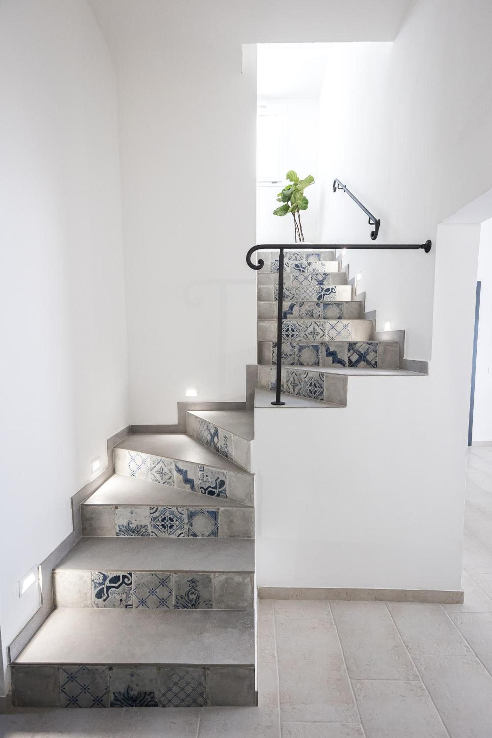 A staircase with patterned tiles and a metal handrail.