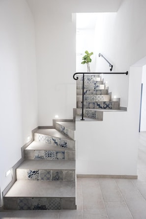 Una escalera con baldosas estampadas y barandilla metálica.