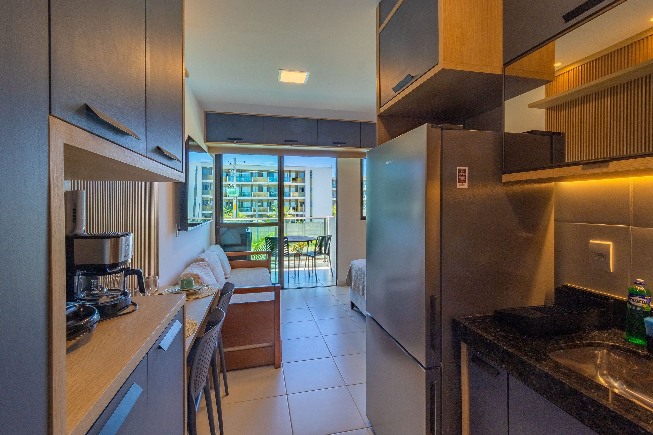Cocina compacta con estufa integrada, refrigerador y comedor con mesa y sillas.