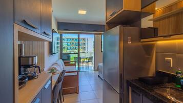 Cocina compacta con estufa integrada, refrigerador y comedor con mesa y sillas.