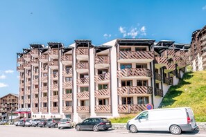 A multi-story hotel with balconies, a parking area, and a clear sky. - Wifi, 10m from ski slopes, balcony, ski locker, 54m², Val Thorens (Val Thorens)