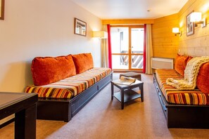 A room with two beds, a small table, and a view of the outside through a door. - Wifi, 10m from ski slopes, balcony, ski locker, 54m², Val Thorens (Val Thorens)