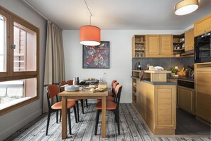 A modern kitchen with wooden cabinets, a dining area with a table and chairs, and a large window providing natural light. - Wifi, 5m from ski slopes, swimming pool, sauna, hammam, balcony, ski locker, 46-48m², Flaine (Flaine)