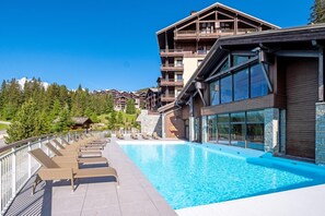A modern hotel with a swimming pool, outdoor seating, and a view of surrounding buildings. - Wifi, 5m from ski slopes, view mountain, swimming pool, sauna, hammam, balcony, ski locker, 49-56m² (Flaine)