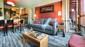 Ein modernes Wohnzimmer mit einem grauen Sofa, einem Holztisch und einem Essbereich mit Stühlen und Tisch.
