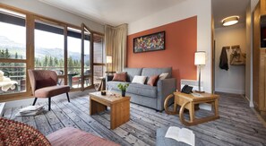 A modern living room with a sofa, armchair, and coffee table, a large window with a view of trees and mountains, and a painting on the wall. - Wifi, 5m from ski slopes, swimming pool, sauna, hammam, balcony, ski locker, 68-80m², Flaine (Flaine)