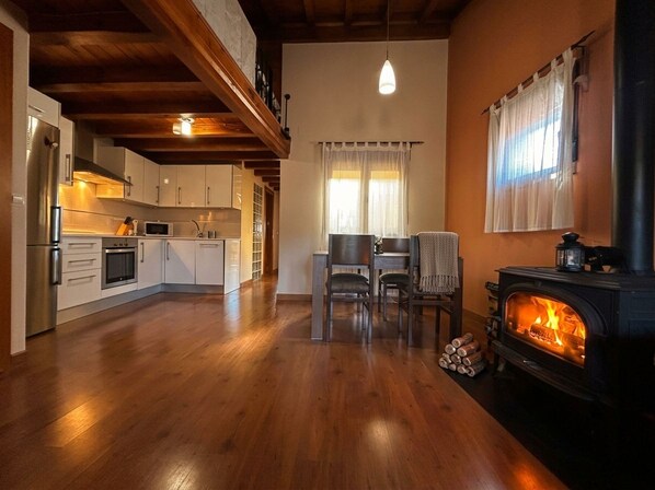 Una cocina moderna con suelo de madera, un comedor con sillas y una estufa de leña.