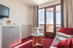 A hotel room with a bed, a desk with a laptop, a television, and a window with a view of snow. - 10m from ski slopes, balcony, ski locker, 21m², Avoriaz (Avoriaz)