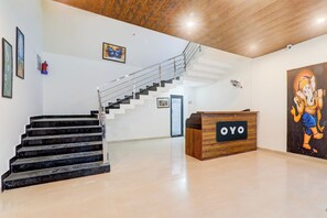 A reception area with a wooden desk labeled 'OYO,' a staircase with metal railings, and a wall with framed artwork. - Hotel O Gomti Nagar Vigyan khand (Lucknow)