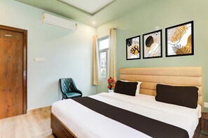 Ein Hotelzimmer mit einem Bett, einem Sessel, einem Fenster mit Vorhängen und Wandbildern.