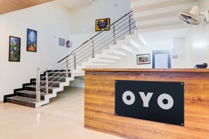 Ein Empfangsbereich mit einem Schild, das 'OYO' zeigt, in einem modernen Gebäude mit Treppe und Kunstwerken an den Wänden.