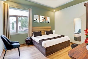 A modern bedroom with a large bed, a chair, a bedside table, and artwork on the wall. - Hotel O Gomti Nagar Vigyan khand (Lucknow)