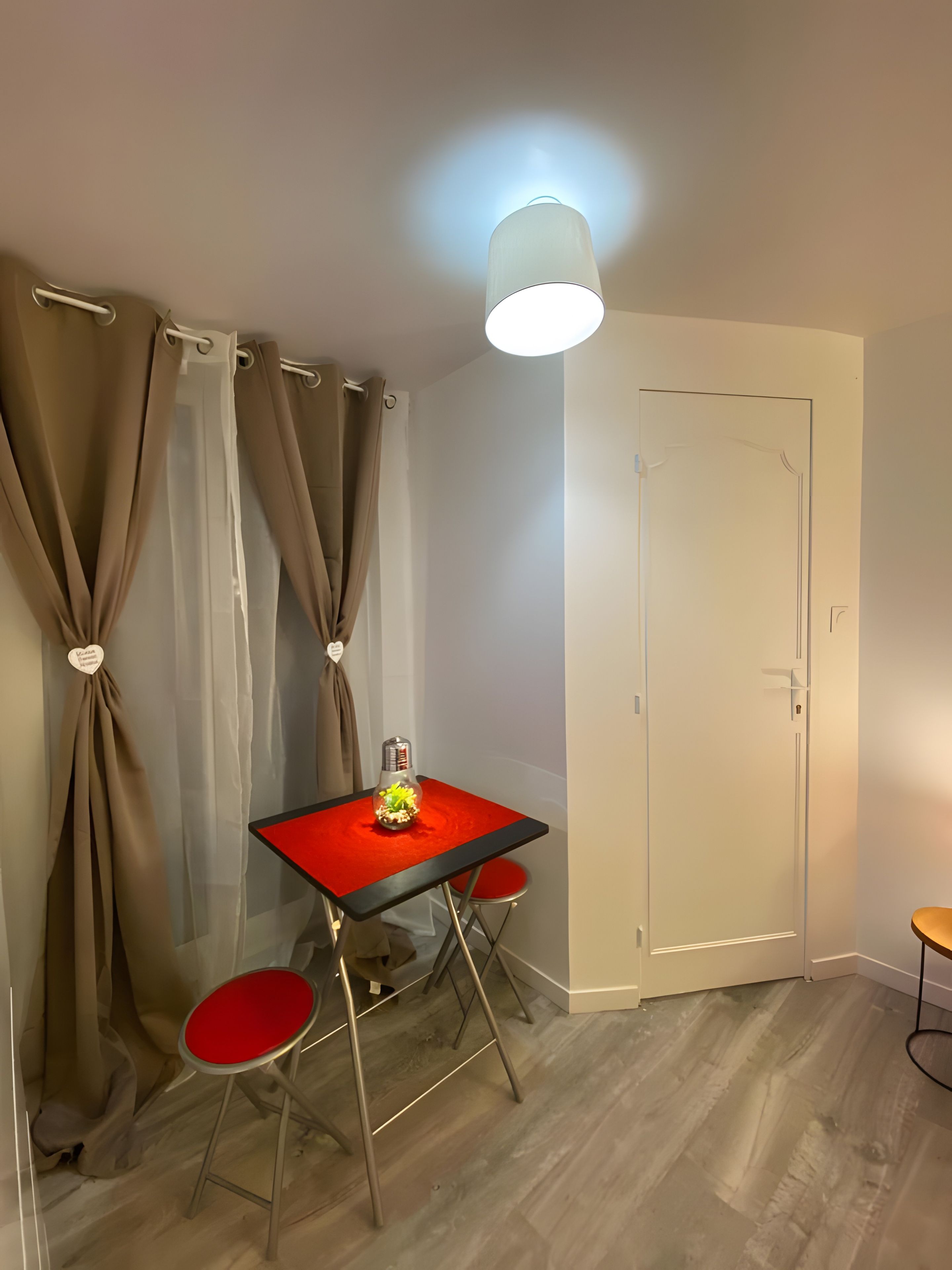 A room with a table, two chairs, a door, and curtains.