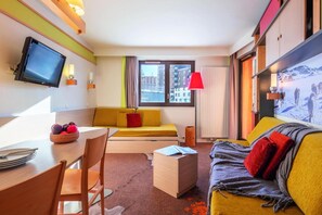 A modern hotel room with a sofa, a dining table with chairs, a television, and a large window with a city view. - 10m from ski slopes, ski locker, 30-39m², Avoriaz (Avoriaz)