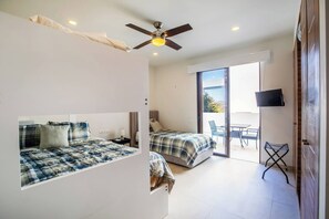 A bedroom with two beds, a ceiling fan, a TV, and a balcony with a table and chairs. - Enjoy a peaceful family escape in Alamar, La Cruz de Huanacaxtle (Cruz de Huanacaxtle)