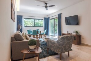 Ein modernes Wohnzimmer mit Sofa, Sessel, Esstisch und Stühlen.