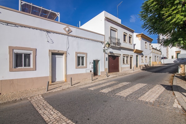 A street with buildings, a cobblestone road, and a clear blue sky.