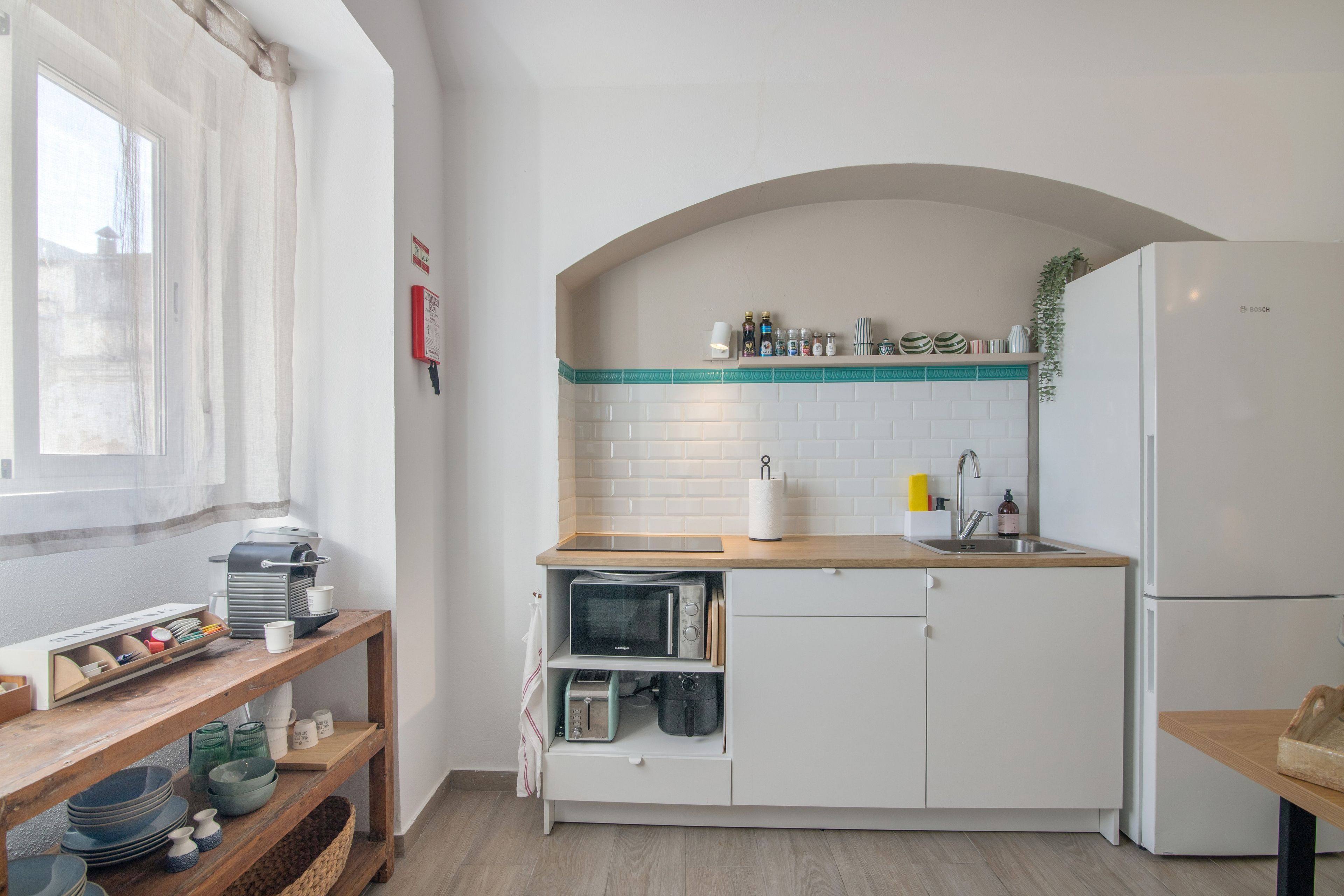 Eine kleine Küche mit weißen Schränken, einem Backofen, einer Spüle und einem Kühlschrank.