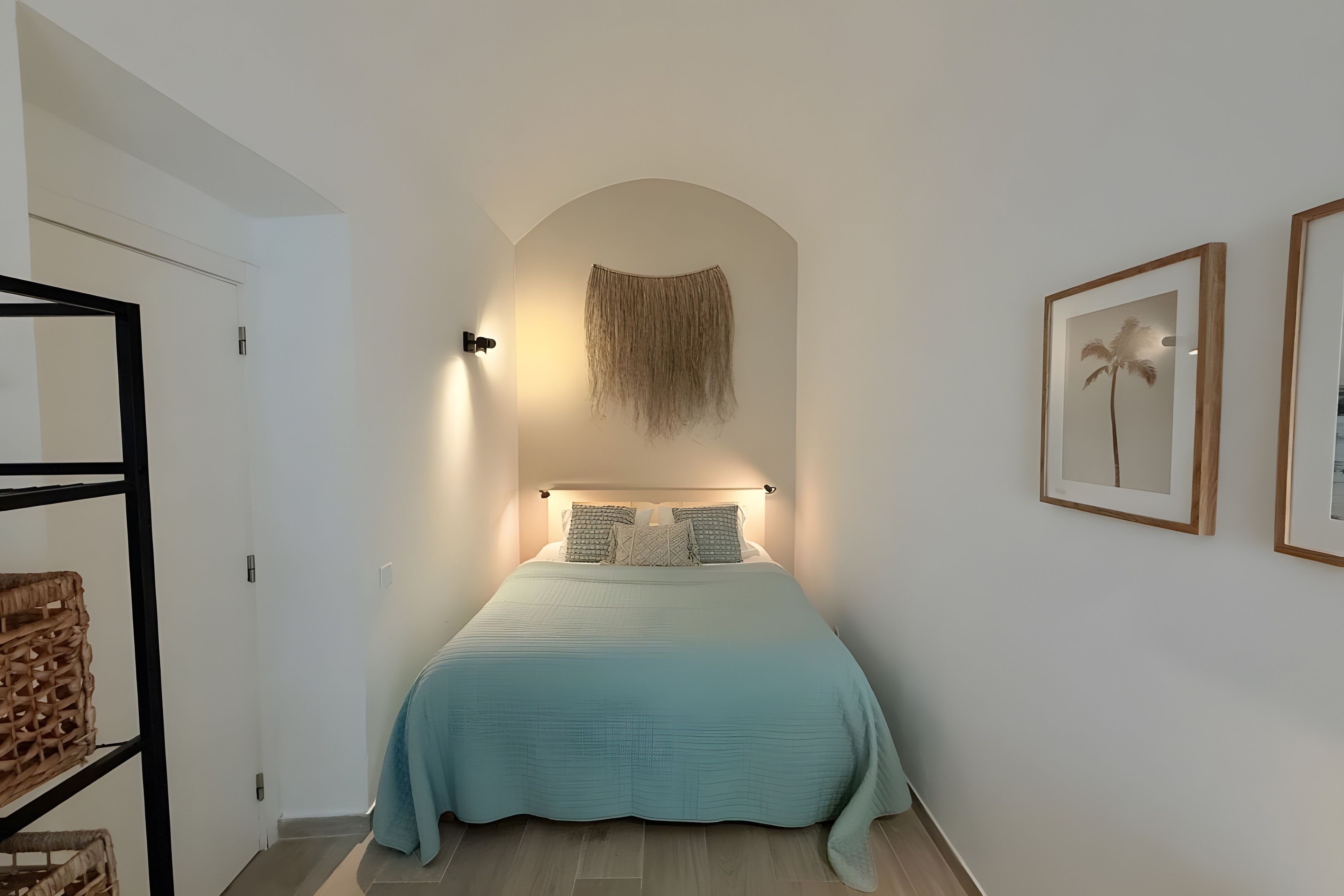 A bedroom with a bed, a hanging tapestry, and two framed pictures on the wall.