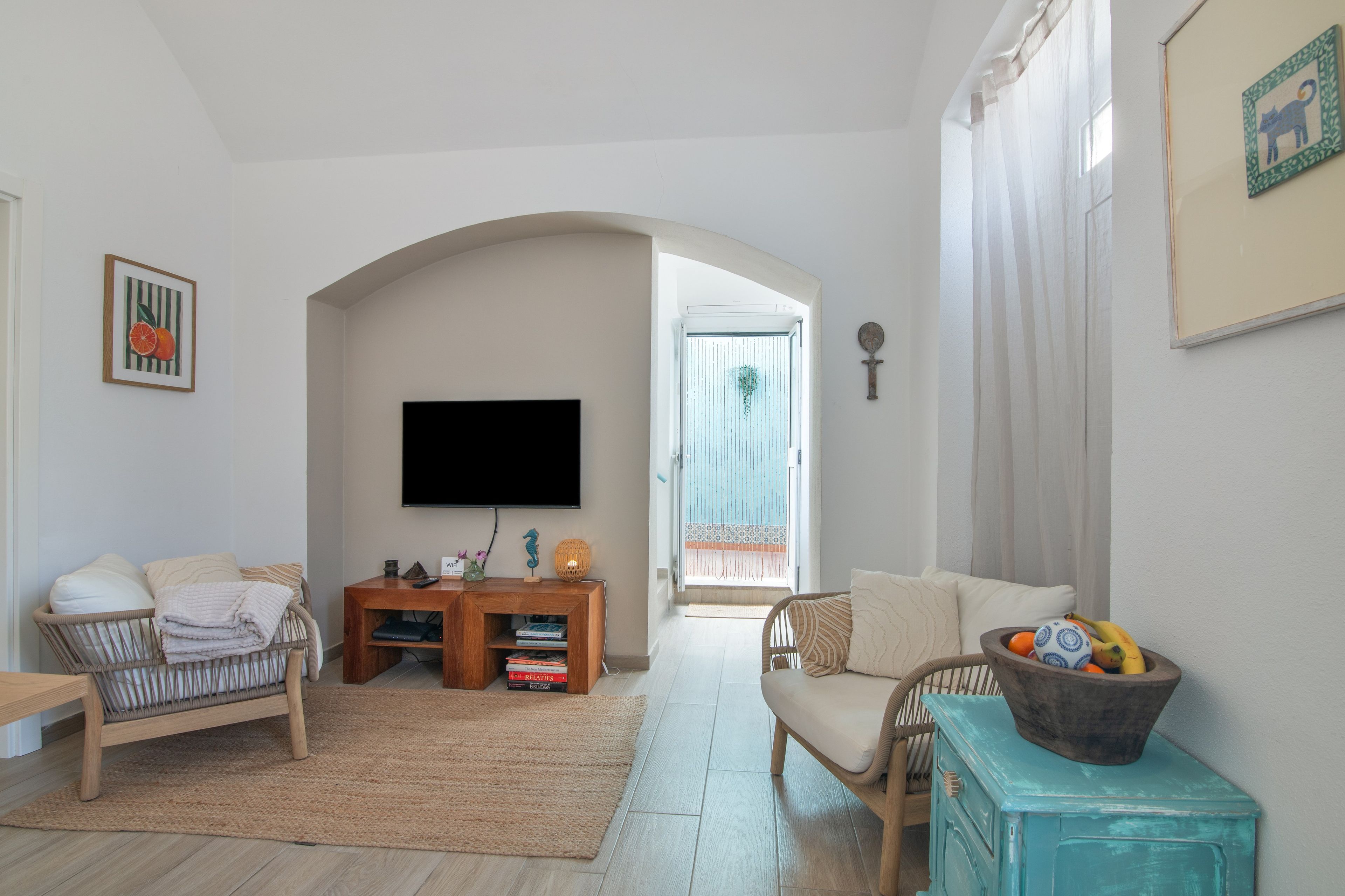 Een woonkamer met een flatscreen televisie, twee banken, een salontafel en een boekenkast.