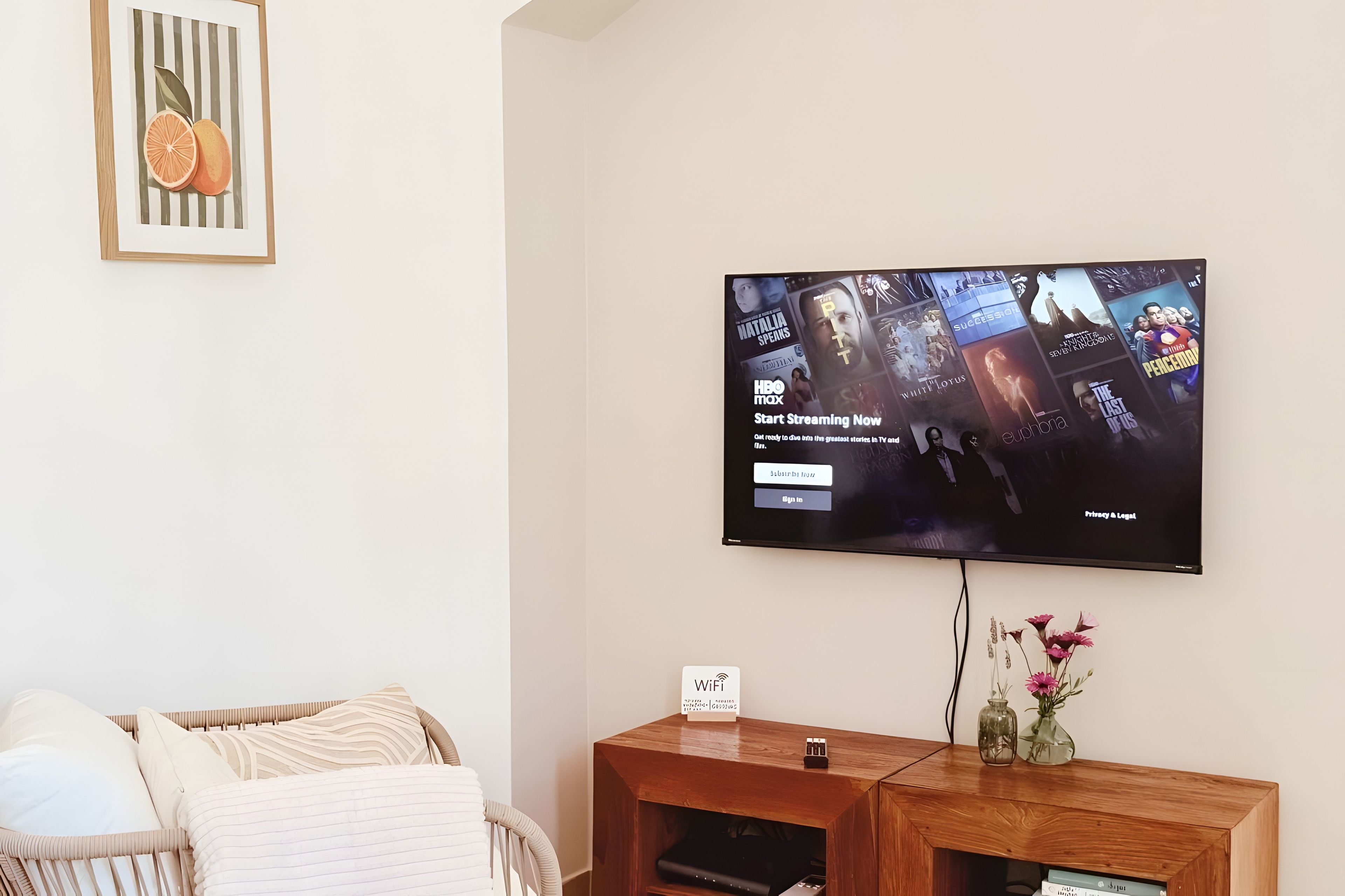 A flat-screen TV mounted on a wall displaying a streaming service interface with various show options.