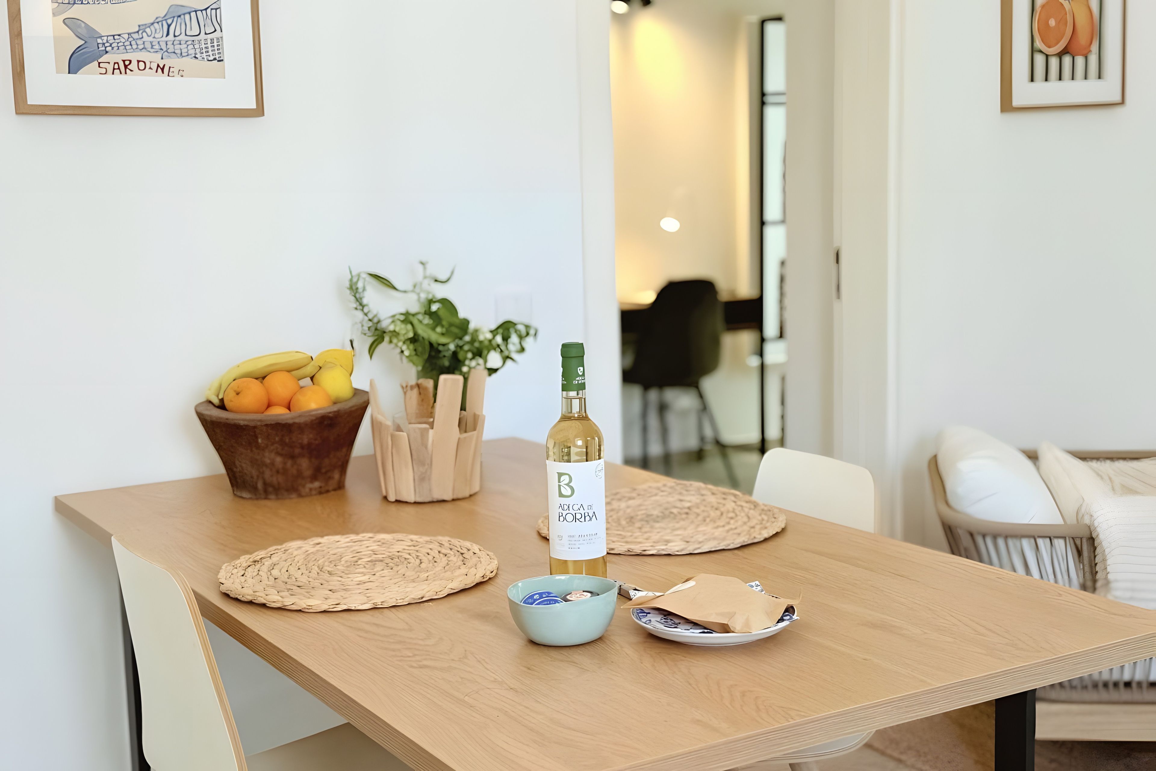 A wooden dining table with a bottle, a bowl, and a fruit bowl.