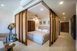 A hotel room with a bed, a desk, a chair, a wardrobe, and a ceiling fan. - Paraíso MarAlma 2BR Rooftop Vista al Mar Bucerías (Bucerías)