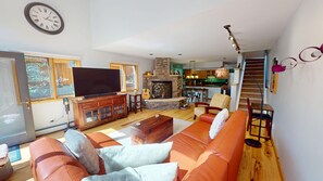 A living room with a television, sofa, fireplace, and a kitchen in the background. - Private Hot Tub, Pet Friendly in Frisco. Spacious Townhouse, Garage, Grill (Frisco)