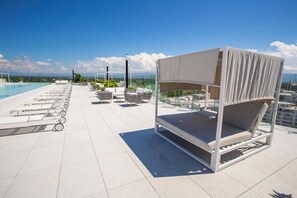 A rooftop pool area with lounge chairs and a canopy bed. - Ocean views in luxury complex. (Nuevo Vallarta)