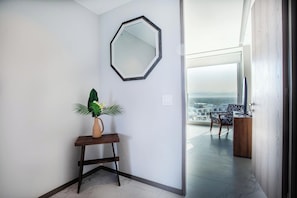 A modern interior with a large mirror, a potted plant, and a view of a balcony with a chair. - Ocean views in luxury complex. (Nuevo Vallarta)