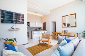 En moderne stue med sofa, sofabord og et spiseområde med stole og bord.