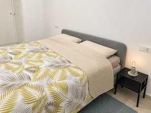 Ett sovrum med en säng, ett sängbord med en lampa och en dörr.
