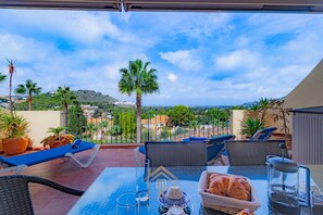 Eine Terrasse mit Esstisch, mit Blick auf eine reizvolle Landschaft mit Palmen und Gebäuden.